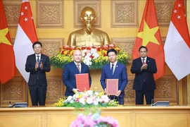 越南政府总理范明政与新加坡总理黄循财共同见证越南友好协会与新加坡国际基金会合作备忘录的签署。图自越通社