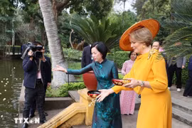 玛蒂尔德王后同阮氏明月夫人在胡伯伯鱼塘给鱼喂食。图自越通社