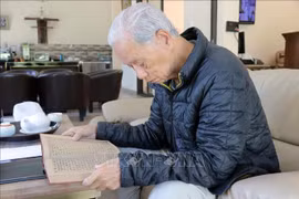 老战地记者严士泰翻阅那本遗失近60年的日记，仿佛回到了烽火连天的岁月。图自越通社