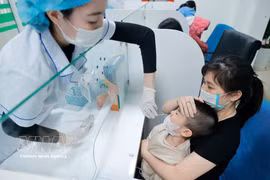 医务人员为患儿采集样本进行流感检测。图自越通社