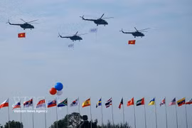载有国旗的直升机在2024年越南国际防务展开幕式上进行飞行表演。图自越通社