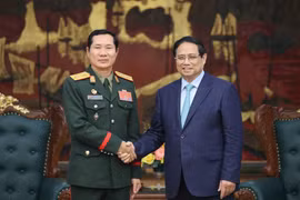 越南政府总理范明政在政府驻地和老挝国防部副部长、老挝人民军总参谋长赛查·库玛西斯。图自越通社