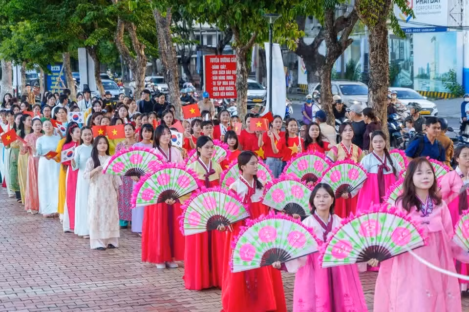 紧随扇子舞队伍之后，身着越南奥黛的游行队伍挥舞两国国旗致意，彰显深厚情谊。图自Vietnam+