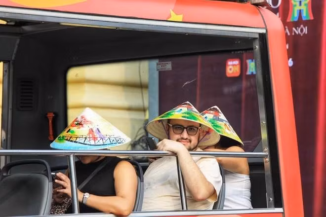 Du khách nước ngoài trải nghiệm tham quan phố cổ Hà Nội trên xe điện.(TTXVN).webp
