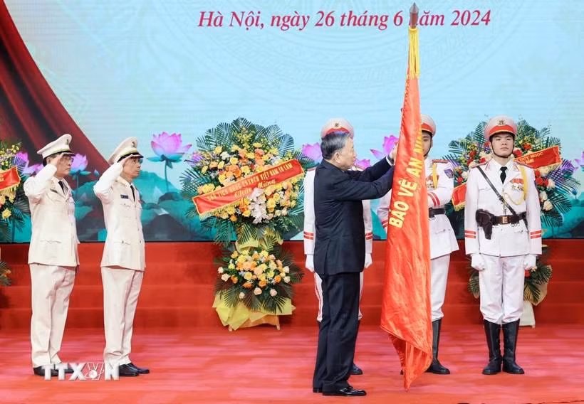 Chủ tịch nước Tô Lâm gắn Huân chương Chiến công hạng Nhì lên cờ truyền thống của Lực lượng kỹ thuật nghiệp vụ Công an Nhân dân. TTXVN.webp