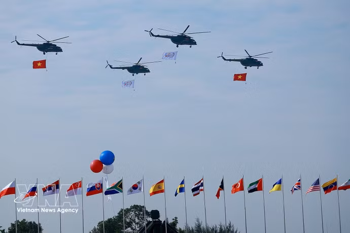 载有国旗的直升机在2024年越南国际防务展开幕式上进行飞行表演。图自越通社
