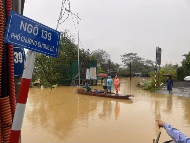 遭受第三号台风影响，河内遭遇洪水，河内还剑郡人民行人外出要用船只。图自越通社