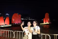 游客们兴致勃勃地与广宁省新推出的旅游产品——红帆船合影打卡。图片来源：越通社