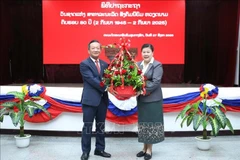 老挝人民革命党中央宣训部副部长薇拉翁·潘塔冯向越南驻老挝大使阮明心送花。图自越通社