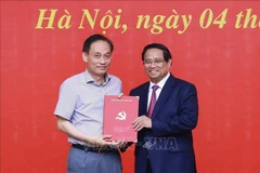 范明政总理向黎怀忠同志颁发中央政治局的决定。图自越通社