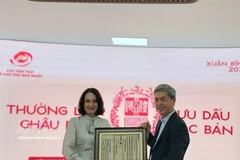 越南国家文书与档案局局长邓青松向俄罗斯驻越大使夫人埃琳娜·贝兹德特科赠送一幅越南国号的木刻版画。图自越通社