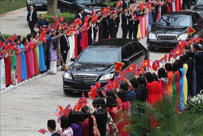 金正恩车队驶进政府总部。穿越南传统奥黛的政府总部干部职员挥舞越南和朝鲜国旗欢迎金正恩来访。图自越通社