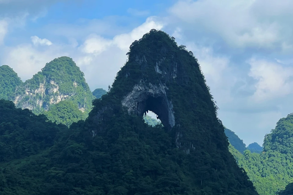 来到高平省茶岭县国瓒社本名村，游客可以欣赏高平山水地质公园汤亨湖群神眼山的美景。周围环绕着绿草覆盖的广阔山谷，一片荒凉又寂静，马群悠闲地吃着草。图自越通社