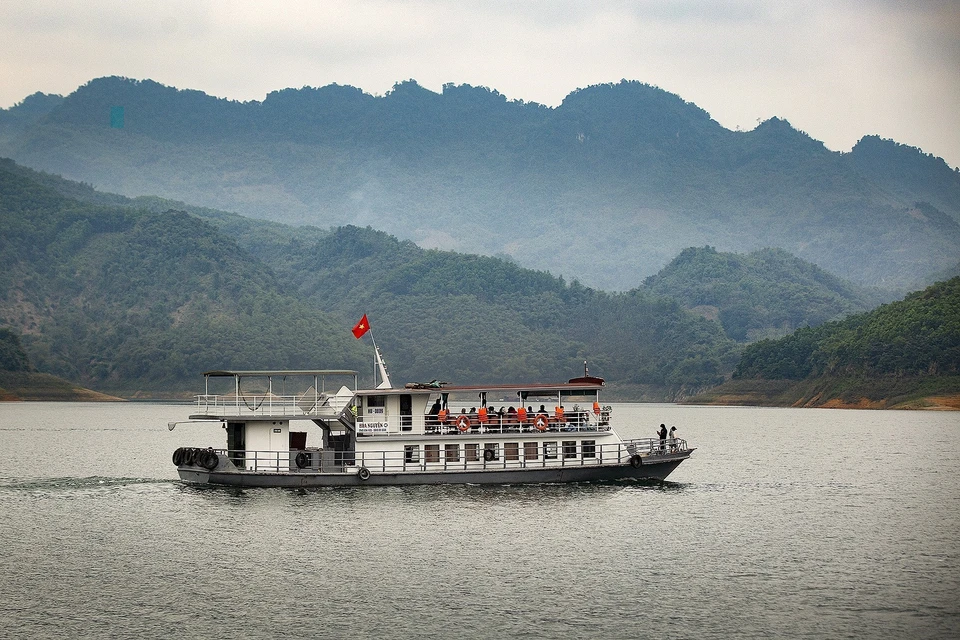 游客乘坐游船欣赏着和平湖两岸的美景。图自越通社