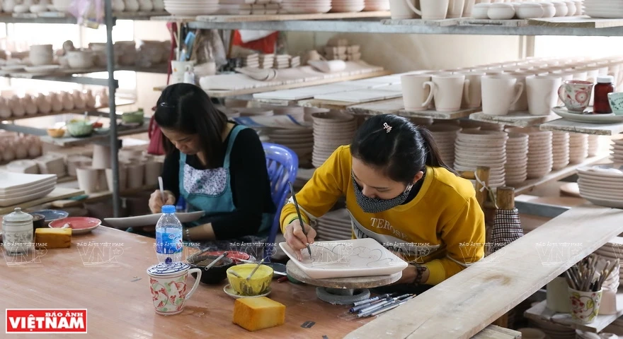 陶瓷工匠认真细致地对陶瓷产品进行彩色浮雕装饰。图片来源：越通社/越南画报