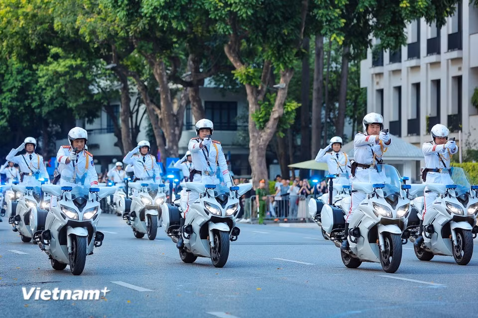 警员展示驾驶摩托车时双手脱把敬礼以及双手脱把射击的高难动作。图自越通社