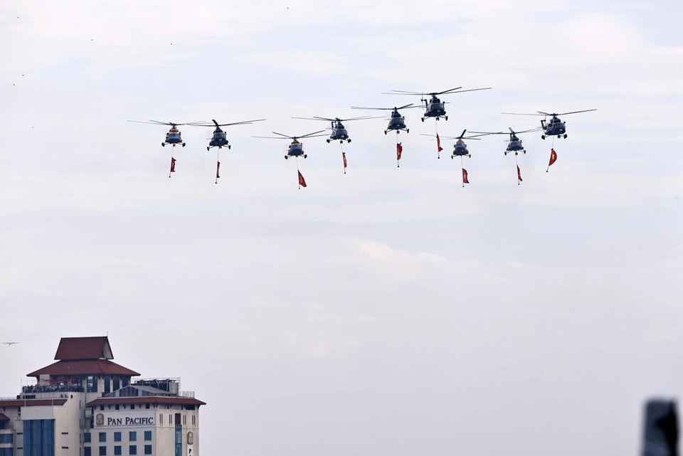 人民空军直升机编队悬挂党旗与国旗飞越河内上空。图自越通社