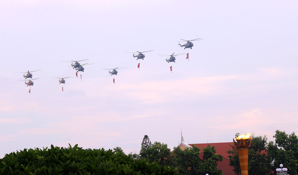 人民空军直升机编队悬挂党旗与国旗飞越河内上空。图自越通社