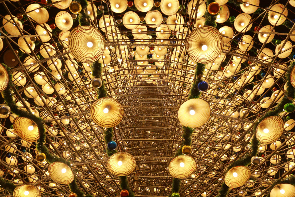 圣诞树以成排斗笠、灯饰、亮片和彩球装点，呈现出神秘而迷人的美感。图自越通社