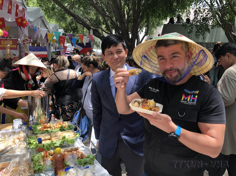 墨西哥毛里西奥区主席塔贝·埃查尔特(Tabe Echartea)在庆祝东盟成立55周年(2022年8月8日)的“东盟加三文化美食节”上品尝越南春卷。图自越通社