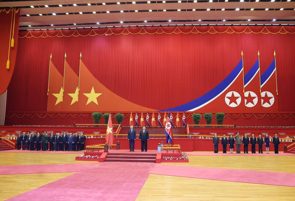 越共中央总书记苏林与朝鲜劳动党总书记、国务委员长金正恩在检阅台上，聆听两国国歌演奏。 图自越通社