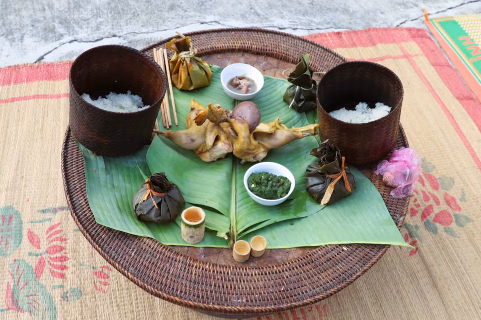 供桌上的祭品包括：白煮鸡、糯米饭、用竹管盛装的米酒、鱼肉丸、用瓷碗盛装的溪苔拌菜等。图自越通社
