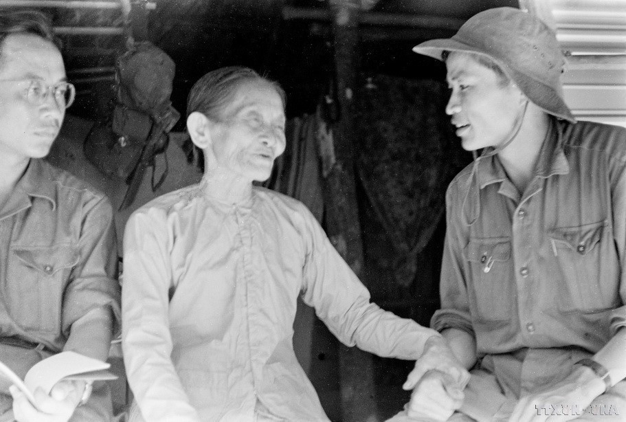 解放通讯社广治省记者杨清风（戴帽子）与广治市（乡级）革命干部培养基地的质（Chắt）母亲交谈。图自越通社