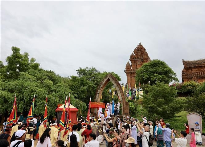 身着传统服饰的民众虔诚步入古塔，手捧祭品敬献祖先与神灵。图自越通社