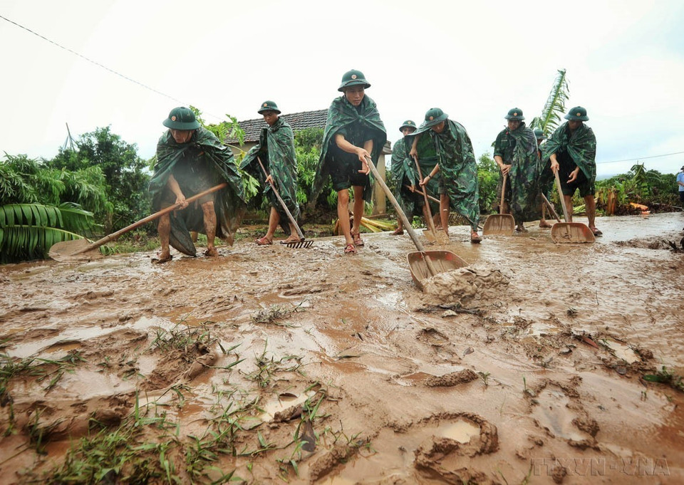 摄影记者记录下了325师战士在台风洪灾过后，帮助陆南县新立乡可吕村村民清理淤泥的感人图片。图自越通社