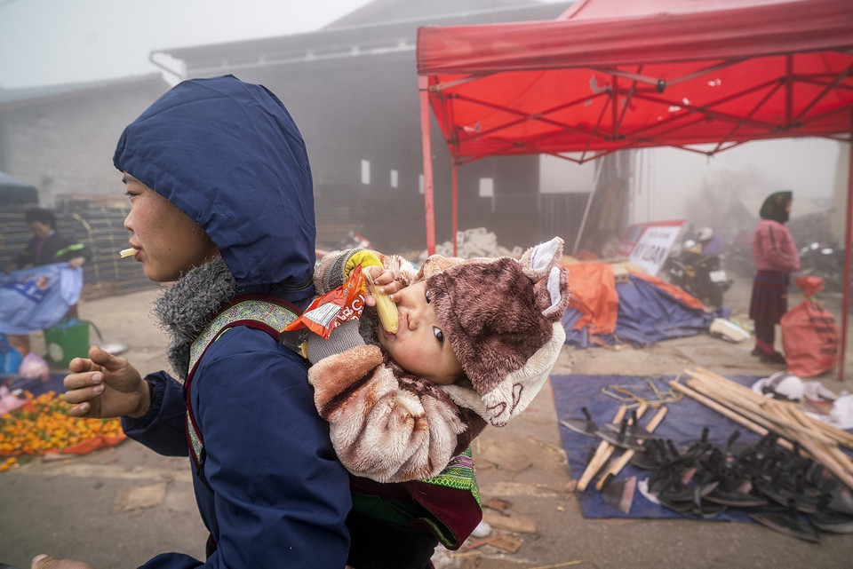 母亲背着孩子赶上河江省同文县庯告集市。图自越通社
