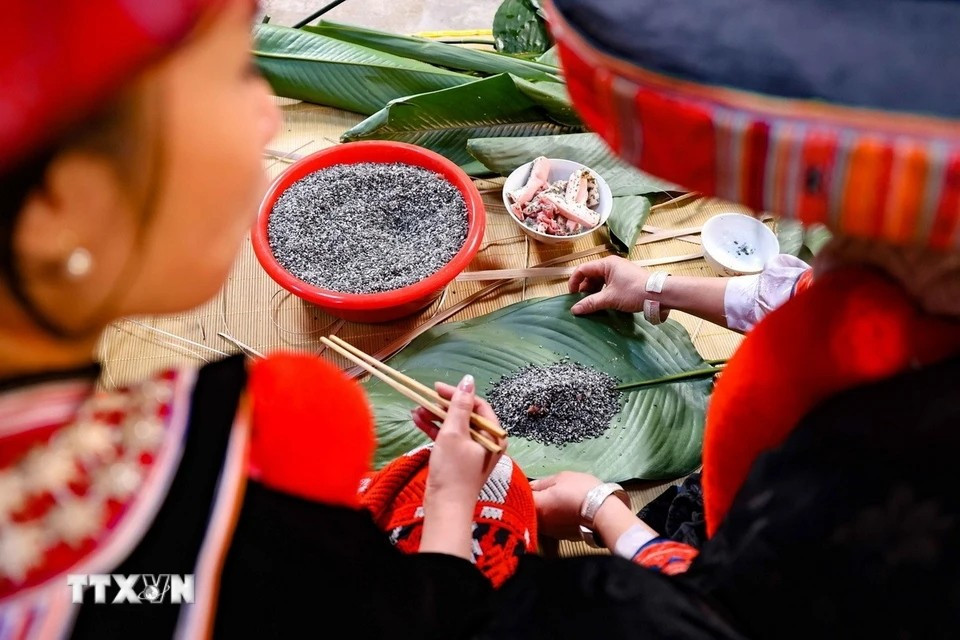 在瑶族家庭中，包粽子主要由妇女承担。她们一边熟练地包着粽子，一边耐心地引导屋里的女孩们学习这项技艺。图自越通社