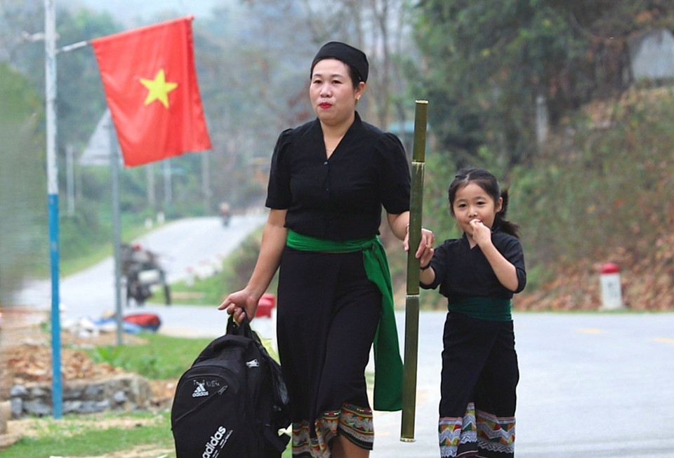 俄都族儿童在祖母和母亲的带领下前往村中的迎雷仪式现场,由巫师(祭师)为其正式命名。图自越通社