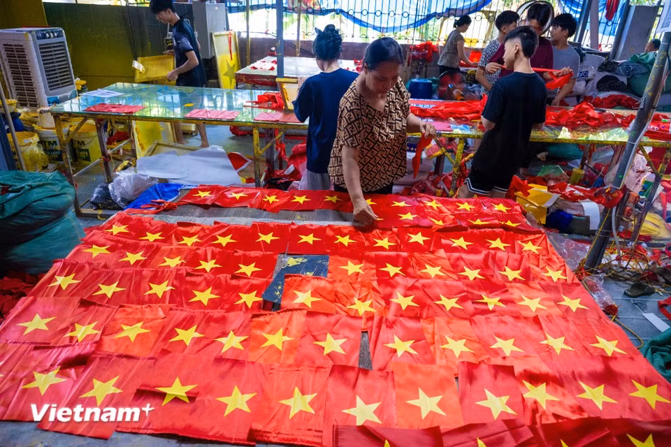 各生产作坊开足马力工作，及时为全国市场供应国旗。图自越通社