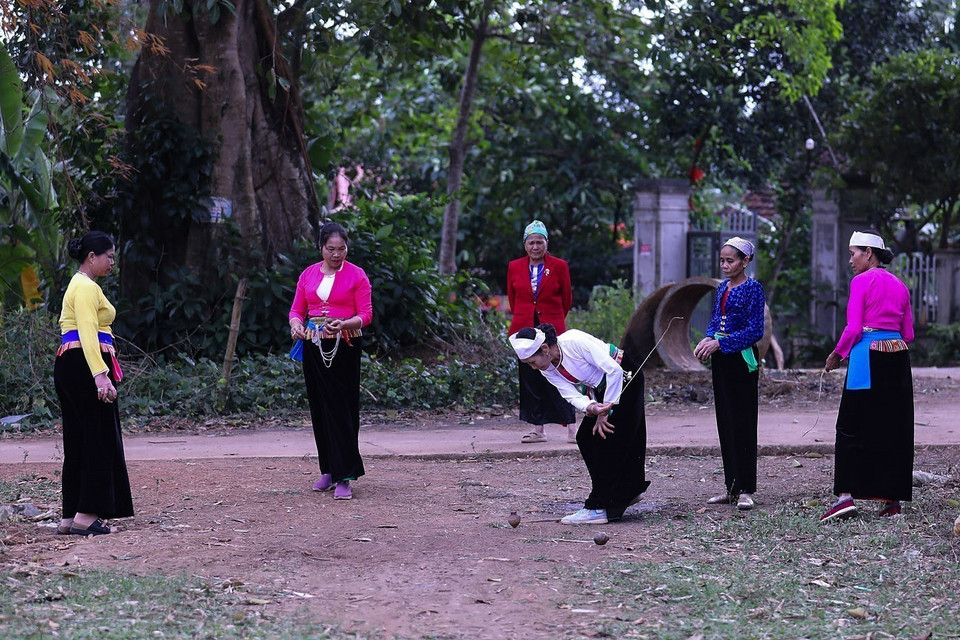 玩家将绳子缠绕在陀螺上并用力拉拽使其旋转，随后同队玩家用力抛出自己的陀螺撞击对手陀螺，使其停转。图自越通社