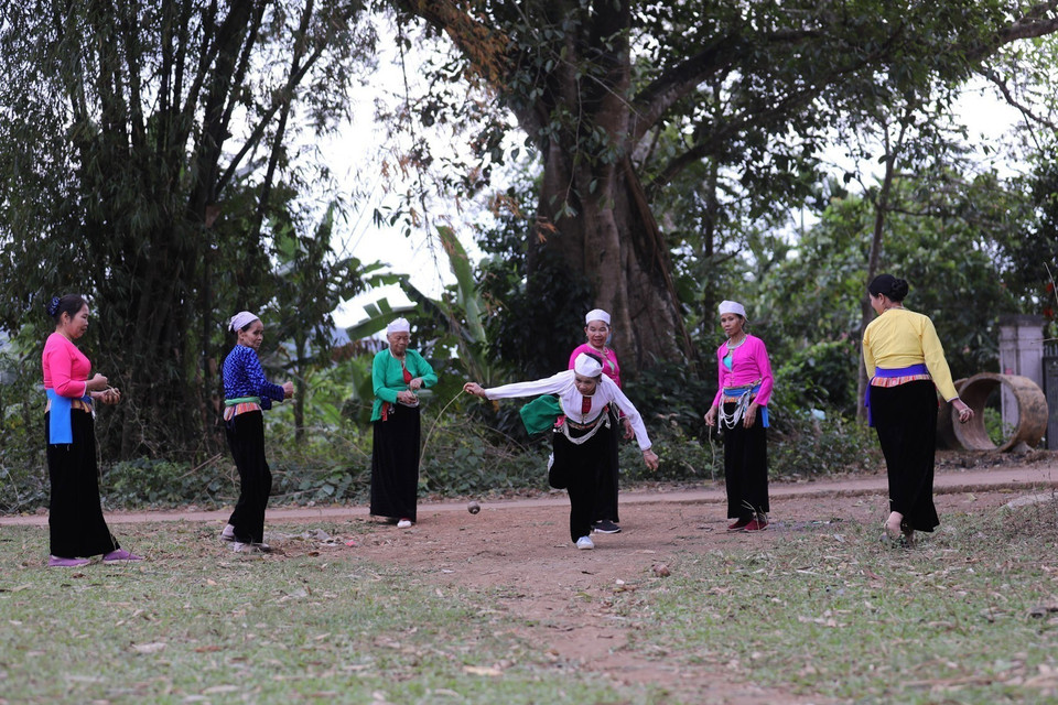 玩家将绳子缠绕在陀螺上，然后用力猛拉使其在地面旋转。图自越通社