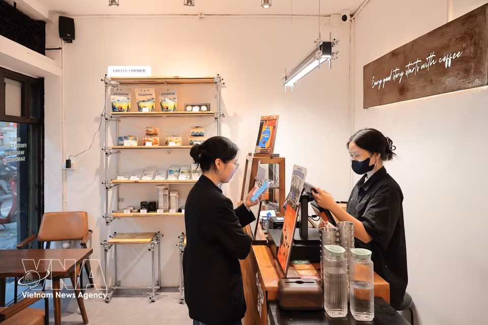 民众在河内潘辉注街的一家饮品店使用扫码支付。图自越通社