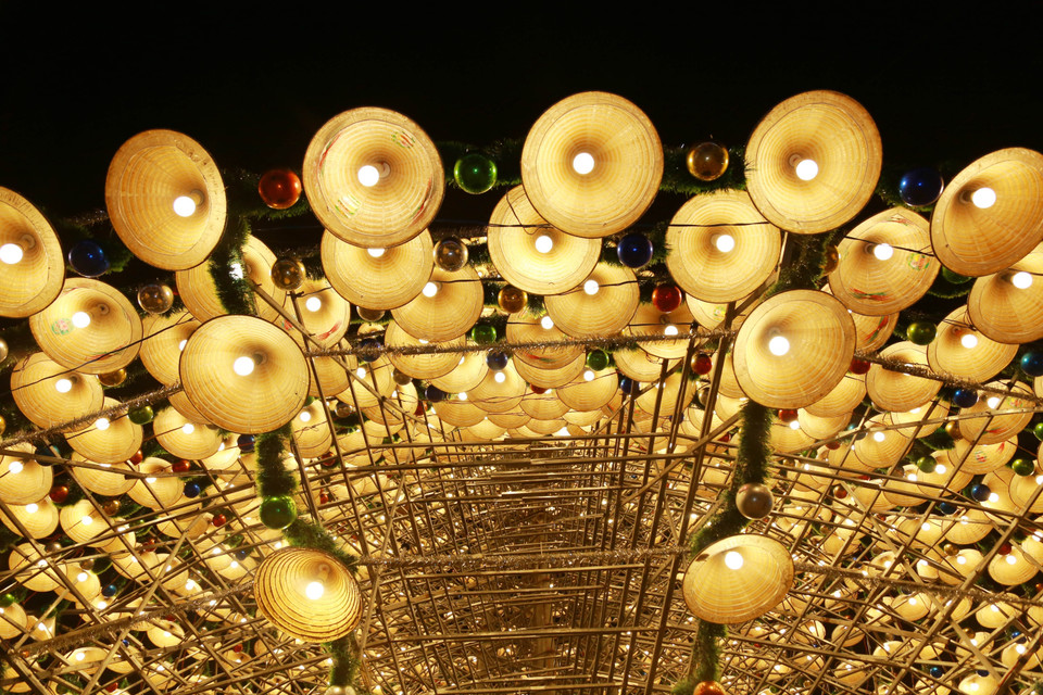 圣诞树以成排斗笠、灯饰、亮片和彩球装点，呈现出神秘而迷人的美感。图自越通社