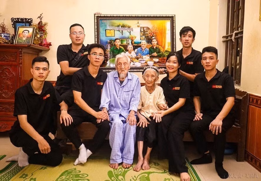 冯光忠（上排右）与Skyline照片修复团队修复了数千张烈士照片，以缅怀那些为祖国独立自由而牺牲的先烈，同社区一道进行“知恩图报”活动。图中：向越南英雄母亲阮氏娥赠送与两个儿子一起吃团圆饭的模拟照片。图自越通社