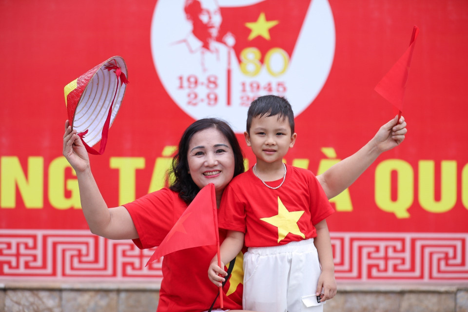 小朋友在家人陪同下外出,与国旗合影,留下纪念瞬间。图自越通社