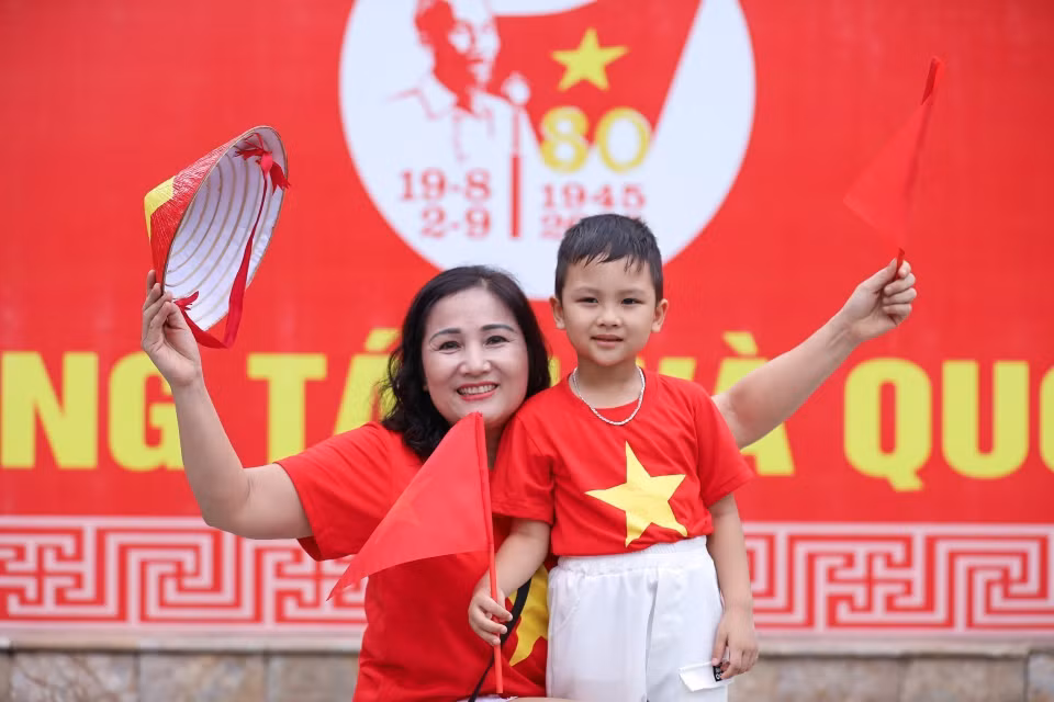 小朋友在家人陪同下外出，与国旗合影，留下纪念瞬间。图自越通社