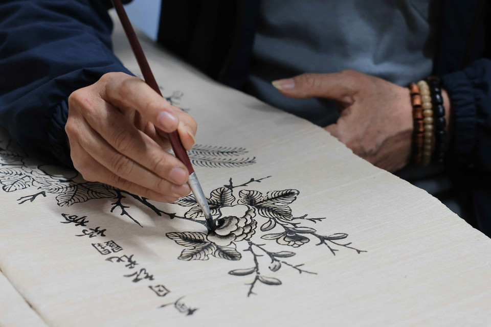 在绘制东湖画时，艺人们常使用毛笔蘸取墨水，在楮纸上细腻作画。图自越通社