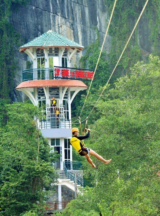 游客在峰衙-几榜国家公园的杵河-暗洞旅游线路体验空中滑索活动。图自越通社