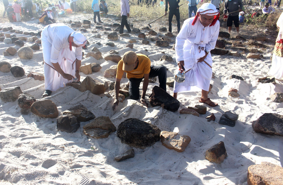 各家族进行掀沙、洒水净扫墓地的仪式。图自越通社