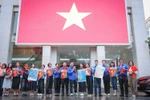 越南通讯社青年团在总部与大型国旗合影留念。图自 越通社