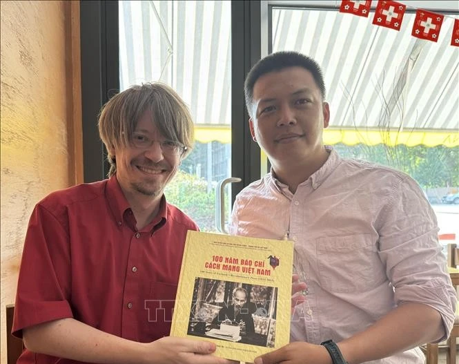 越通社记者向瑞士共产党总书记马西米利亚诺·阿伊赠送礼物。图自越通社