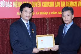 向老挝大使（左）授予“为各民族和平友谊纪念章”。（图片来源：越南共产党电子报） 