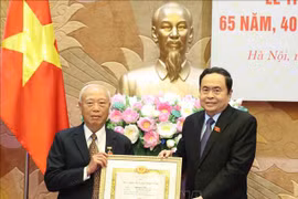 越南国会主席陈青敏向原越共中央政治局委员、原国会主席阮文安同志授予65年党龄纪念章。图自越通社