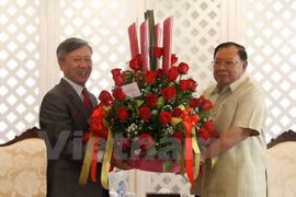 越南驻老挝大使阮孟雄（左）向老挝新任国家主席沃拉吉赠送鲜花