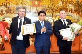 河内市人民委员会主席阮德种向米歇尔·多比尼克先生与雷米·热内维先生授予“致力于首都建设事业”称号。（图片来源：越通社）