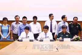 越通社社长阮德利（左前）、河内市人民委员会主席阮德钟（中）和《人民军队报》总编范文训少将共同签署签工作配合计划。（图片来源：越通社）
